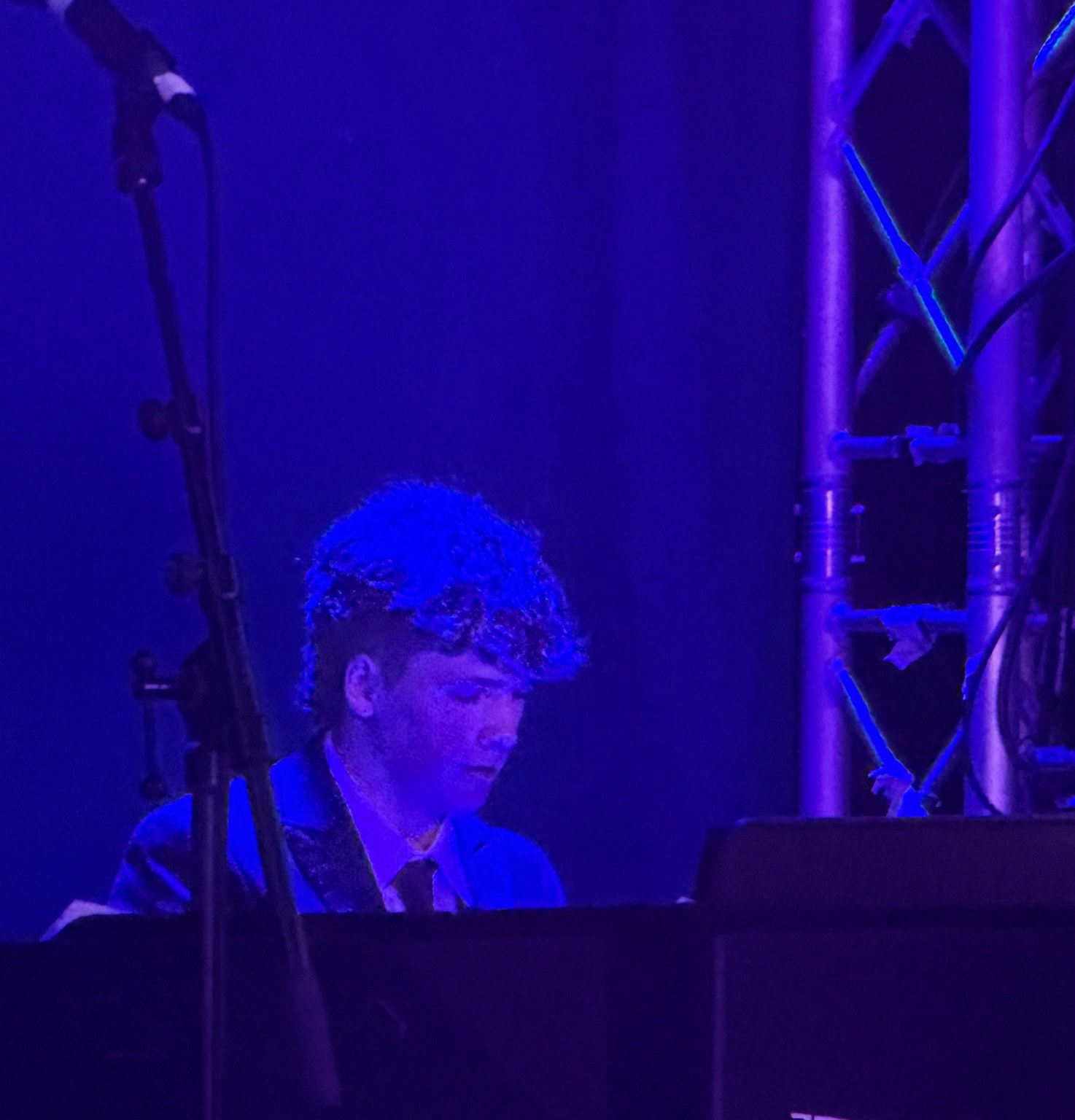 Ben playing keyboard on stage with Warwick Big Band, lit in blue stage lighting